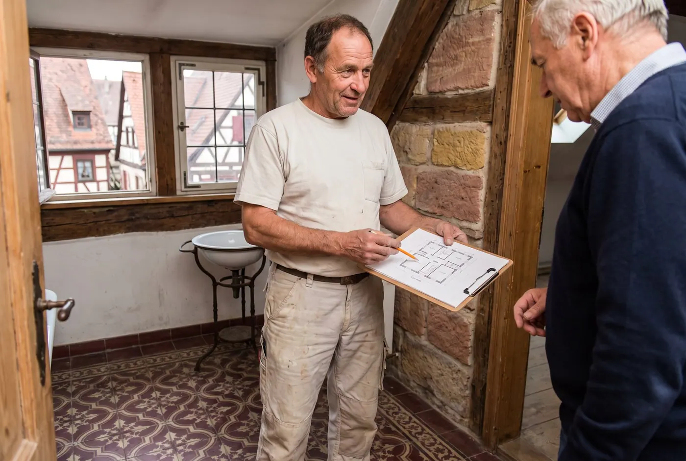 Fachkraft und Eigentümer besprechen den Leitungsplan in einem Baudenkmal